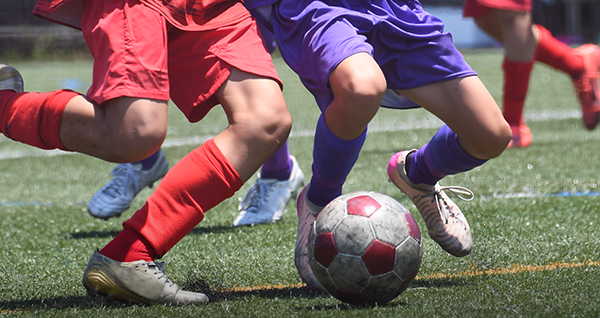 サッカーをする数人の選手の激しく動いている脚とボールの写真