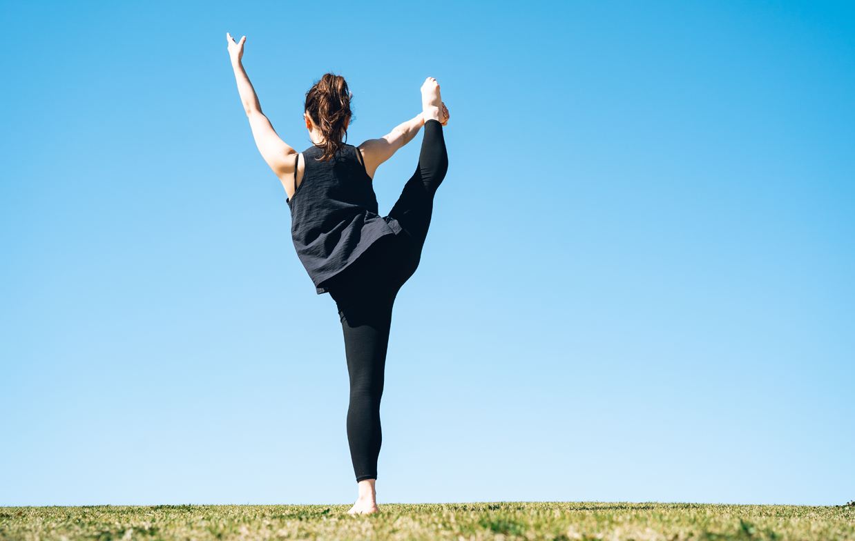 アウトドアでY字バランスをとる女性アスリートの写真