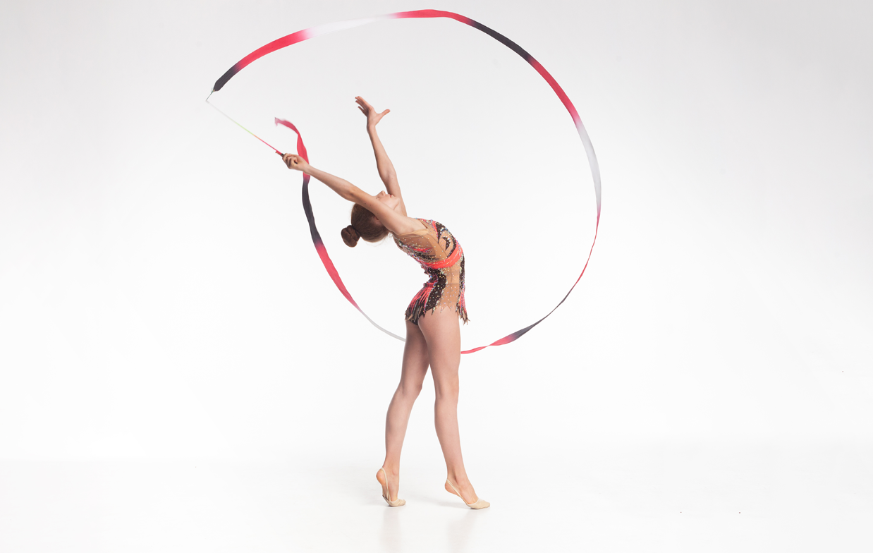 新体操のバトンで空中に円を描く女性の体操選手の写真