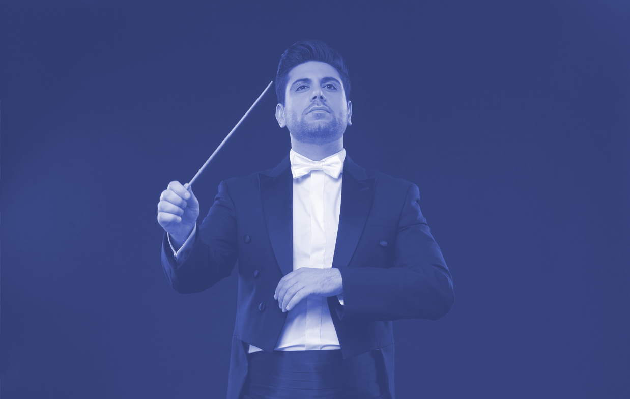 オーケストラに向かってタクトをふる指揮者の写真