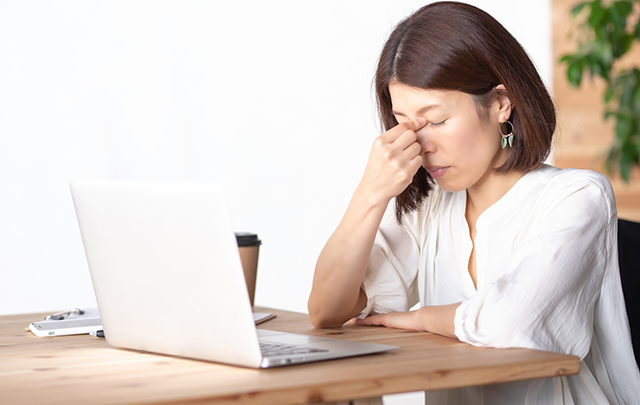 パソコン画面疲れで目を抑える女性の画像