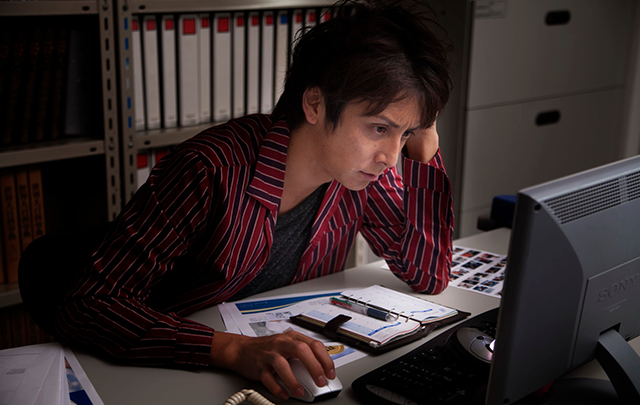 薄暗いオフィス、徹夜でパソコンに向かっているビジネスピープルの画像