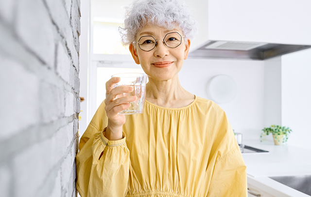 寝る前にいっぱいの水を飲むシニア女性の画像