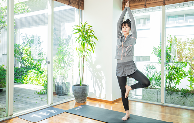 背筋をピンと伸ばしてフィットネスヨガをしている女性の画像