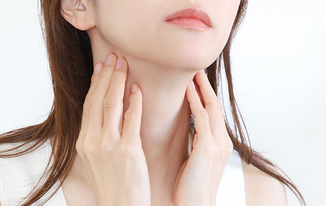 首のリンパ節を手で押さえている女性の画像