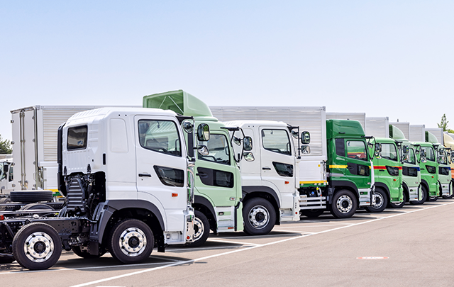 大型の配送トラックが駐車場に並んでいる様子の画像