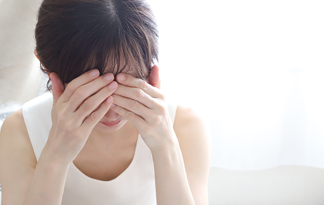 頭痛で頭をかかえる女性の画像