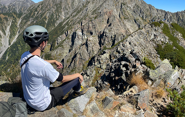 登山途中で休憩している男性登山者の画像