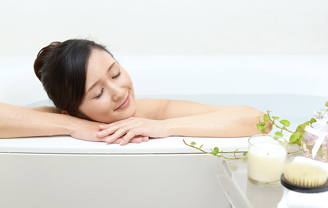 湯船の淵に寝そべりリラックする女性の画像