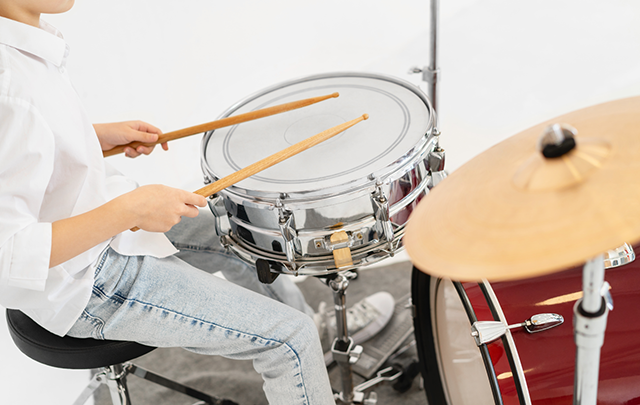 ドラムを叩き、リズムをとる少年の画像