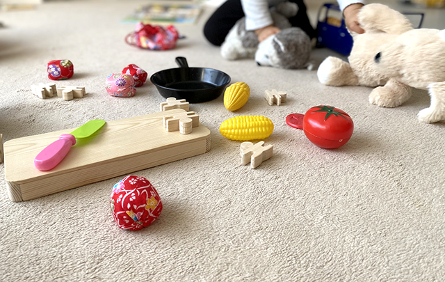 カーペットの上におもちゃが散らばり雑然とした部屋の画像