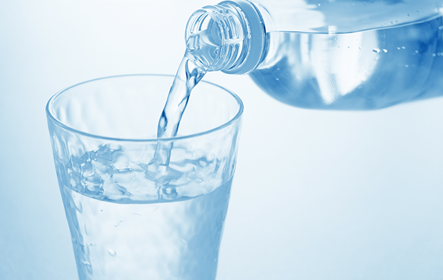 ペットボトルからミネラルウォーターをコップに注ぐ様子の画像