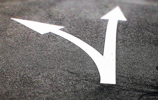 まっすぐ進むか遠まりをするか選択を象徴する道路の矢印の画像