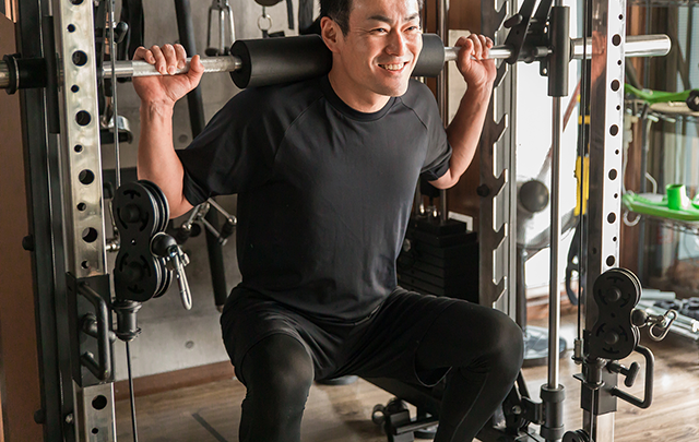 トレーニング器具で背筋に重量のある負荷をかけ鍛える男性の画像