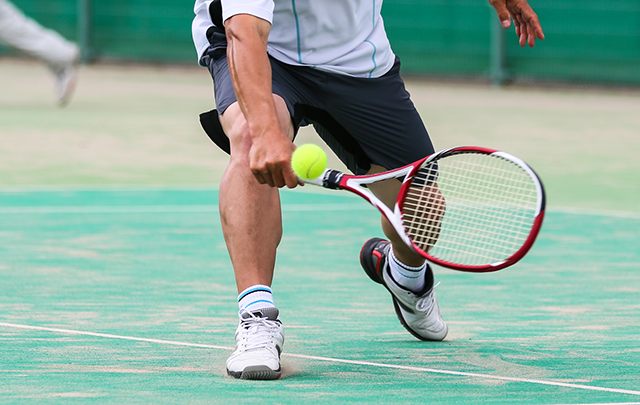 緩急のテニスボールに追いついてラケットで打ち返そうとするテニス選手の画像