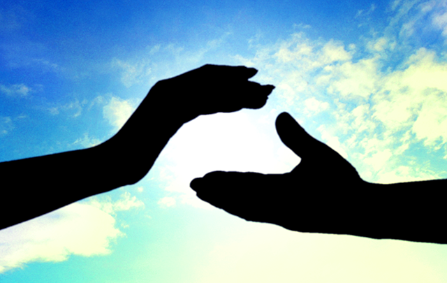 太陽の前で男女がてをつごうとしている画像