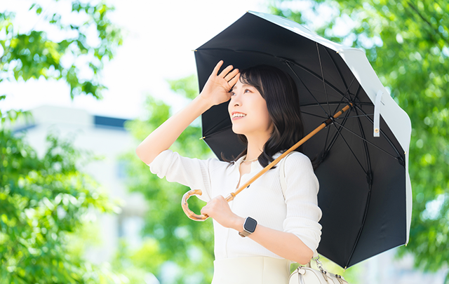 緑の樹木がストリートを日傘をさして額のあえをぬ風女性の画像