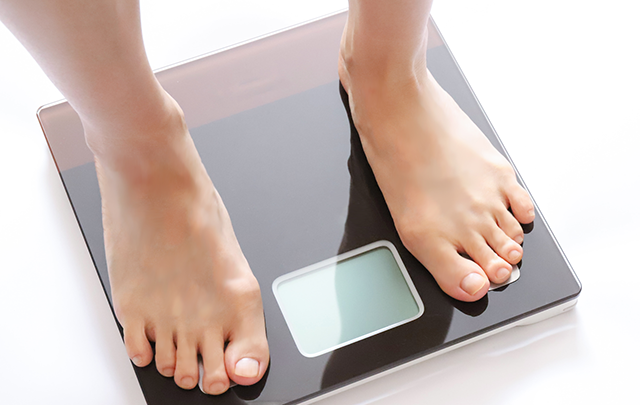 体重計に乗っている男性の素足の画像