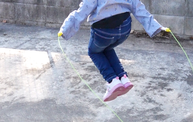 ゆきが降った後、庭先で縄跳びをする少女の後ろ姿の画像