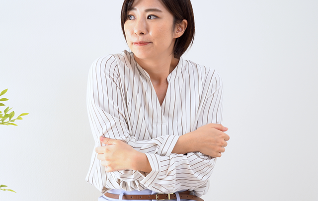 部屋の中央で寒さで腕で身体を抱える若い女性の画像