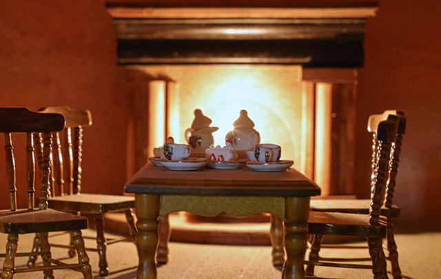 木のテーブルとチェアがある暖炉前の暖かい室内の画像