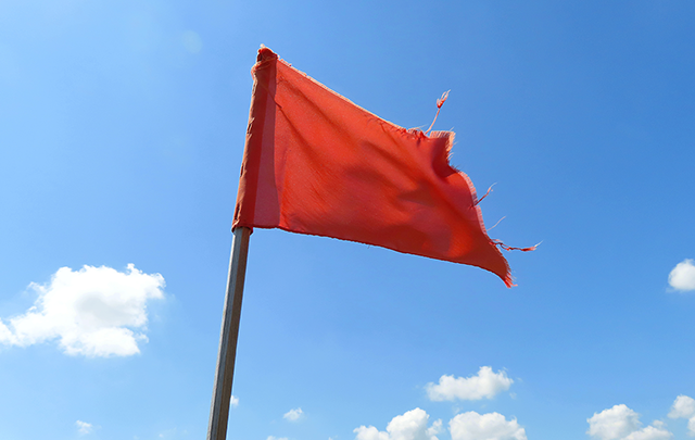 青空の下、赤い旗一本立っている画像
