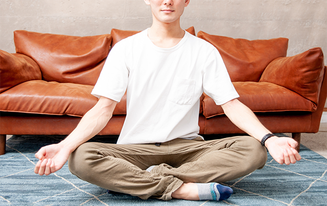 リビングで瞑想して内面に意識を向ける若い男性の画像