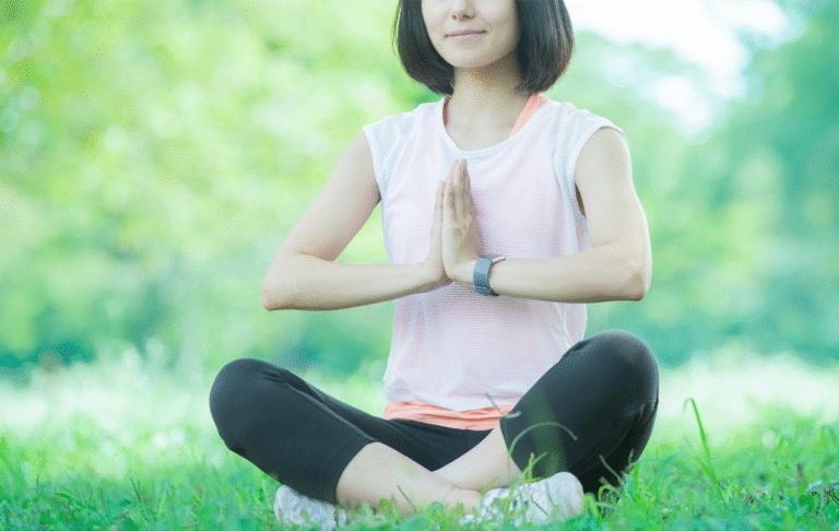 公園の芝生の上で、禅のポーズをする若い女性の写真