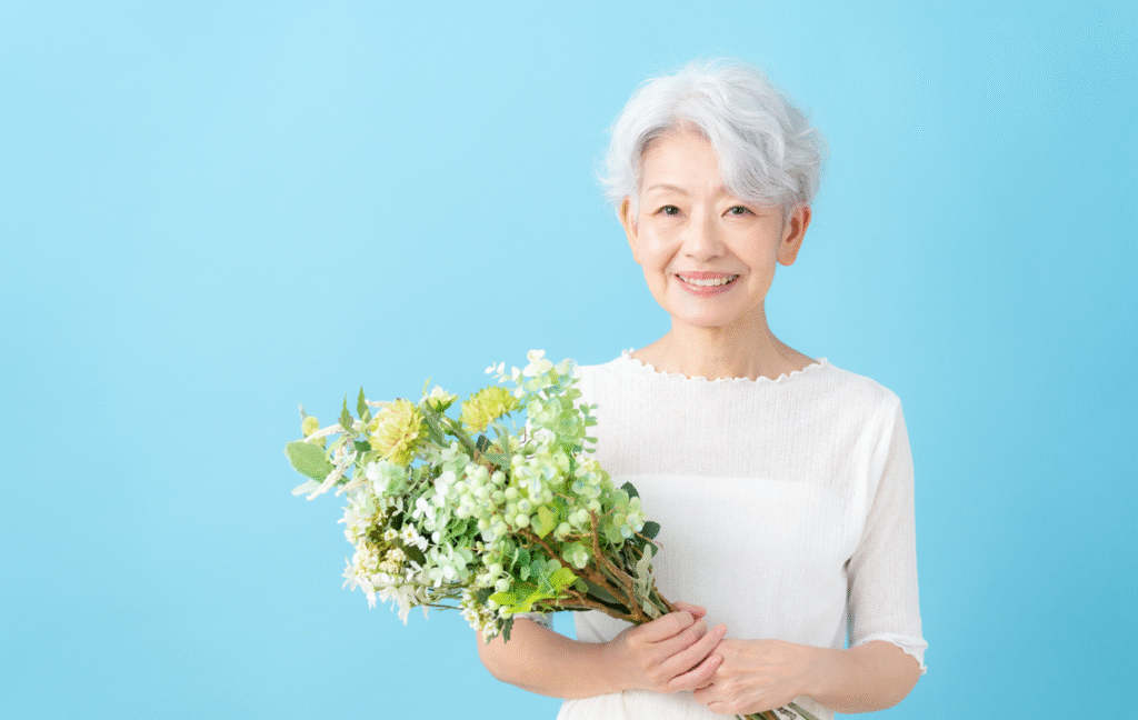 ブルーバックを背景に花束を持つ高齢者の写真