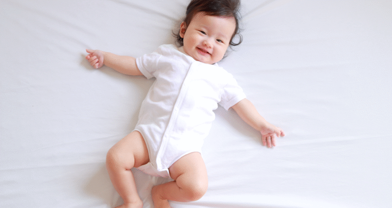 ベッドの上で大の字に寝ている赤ちゃんの画像