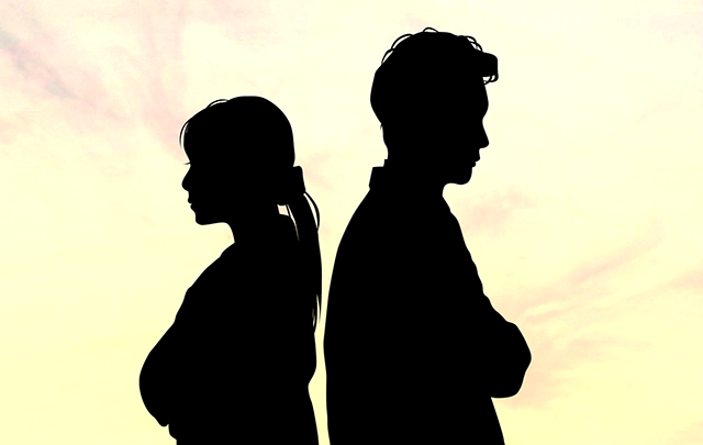 互いに背中を向けて自己主張する若い男女の画像