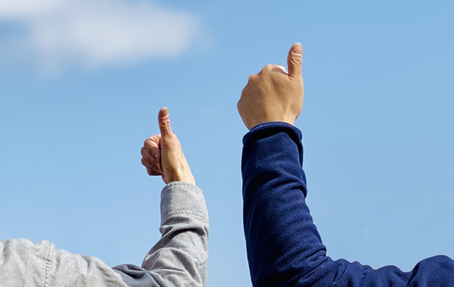 青空の現場でスタッフ同士で互いに親指を立てて合図を送る画像