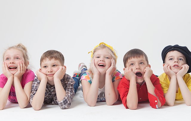 全員がヒジをついて寝そべってすきまなく並んで楽しむ５人の外国人小学生の画像