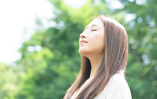 公園で深く深呼吸している女性の画像
