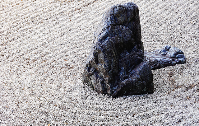 枯山水石庭の一つの位置を取り巻く渦上の砂麺の画像