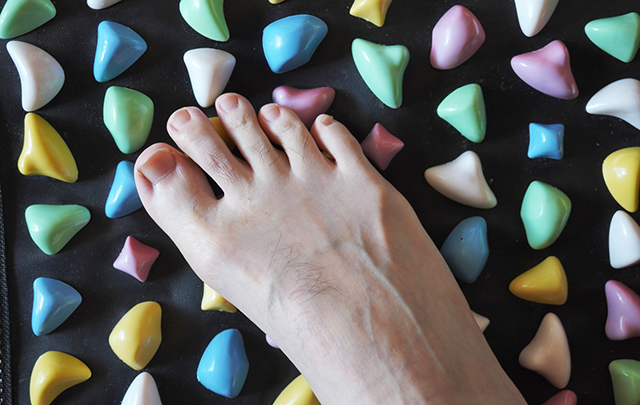 足ツボを刺激する足ツボマットの上に乗る裸足の画像