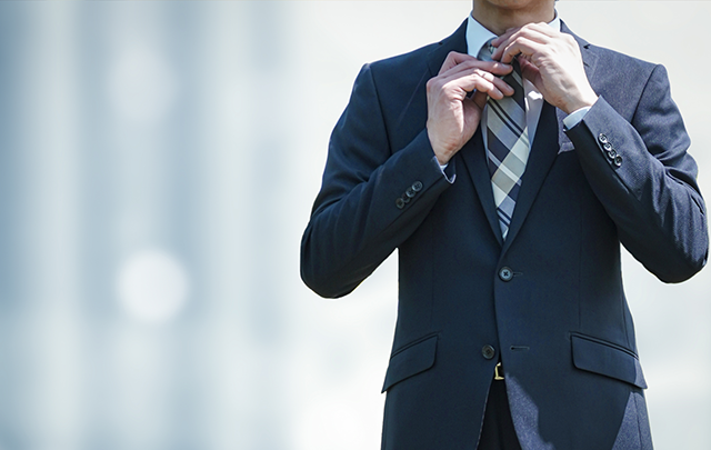 ビルのラウンジでネクタイを整え直す男性ビジネスピープルの画像