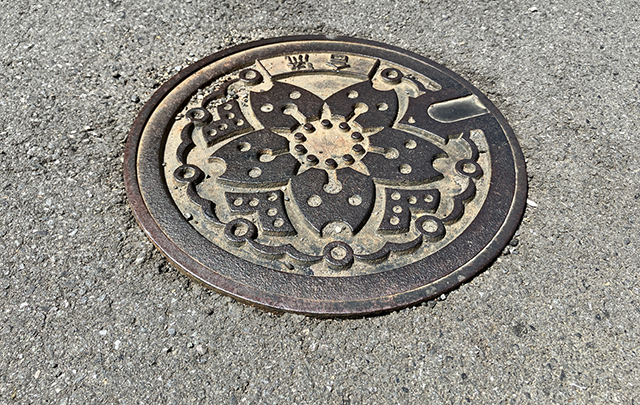 道路にある円形のマンホールのふたの画像