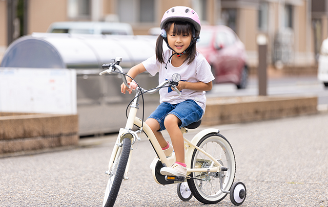 ヘルメットをかぶって安全を確保して自転車の初乗り練習ウィをする幼女の画像