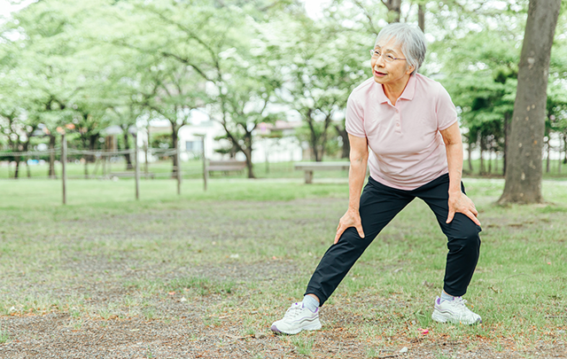 公園の中で朝の体操を続けている高齢女性の画像