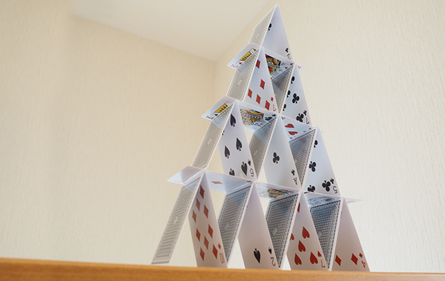テーブルの上にトランプで組まれたピラミッド型のトランプタワーの画像