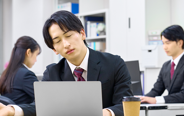 オフィスで居眠りしかかっている男性社員の画像