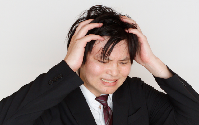 頭を抱え髪を乱す亜dん性ビジネスマンの画像