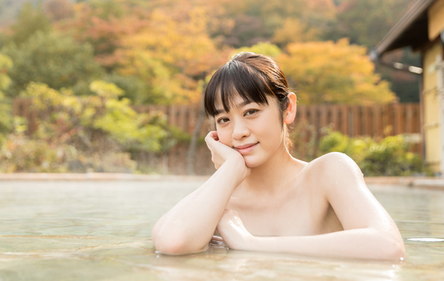 女性が温泉に浸かって余裕のボーズをとる画像