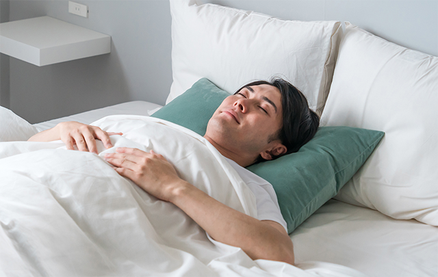 睡眠の質を高めて寝ている男性の画像