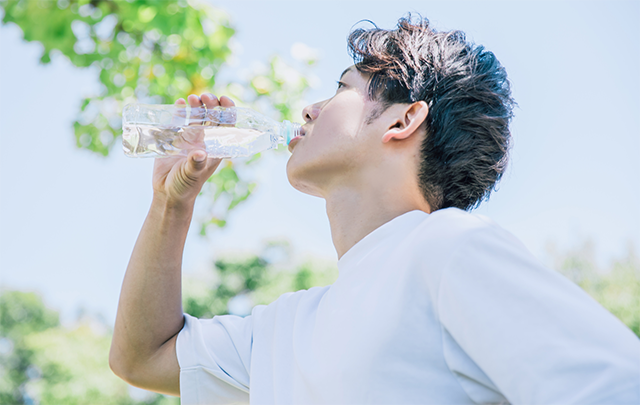 公園で水分を補給している男性の画像