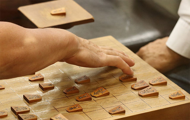 将棋盤上で駒を打つところの画像