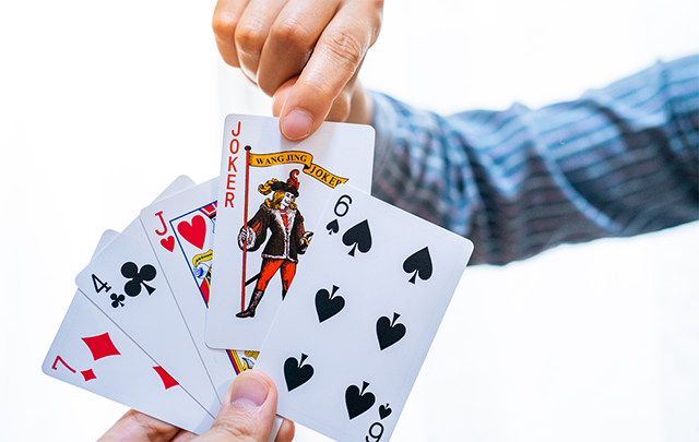 トランプの「ババ抜き」で、ジョーカーのカードを引きかけて選択をあやまっている男性の手元の画像