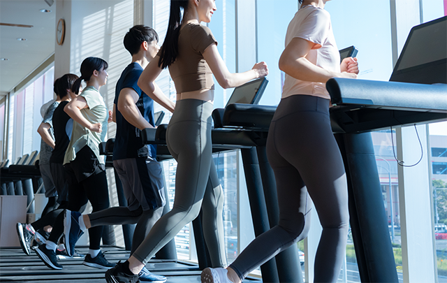 ジムのランニングマシンで鍛える人たちの画像
