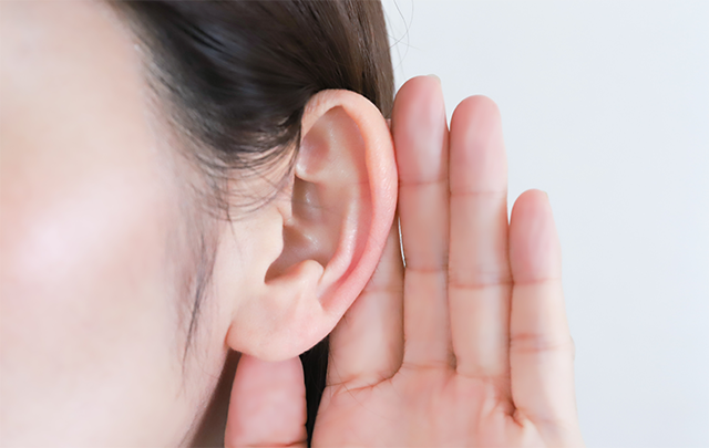 女性が耳の後ろに手を当てて聞き耳を立てている画像